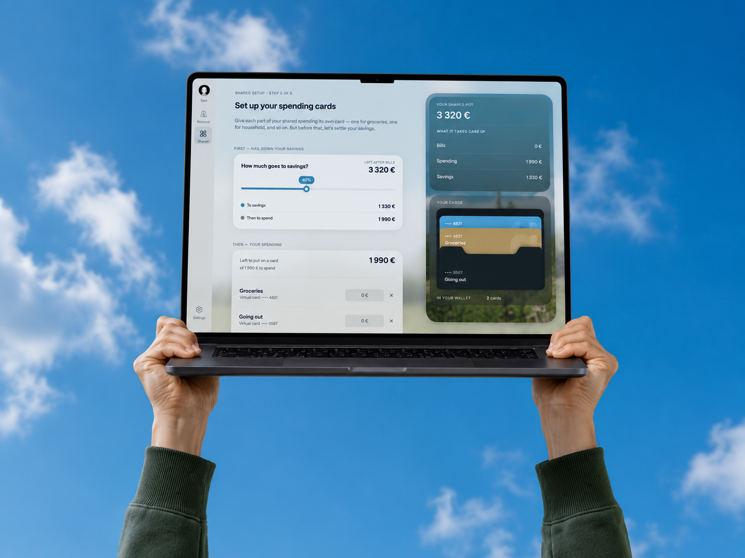 The couples banking app running on a laptop, held up against a blue sky